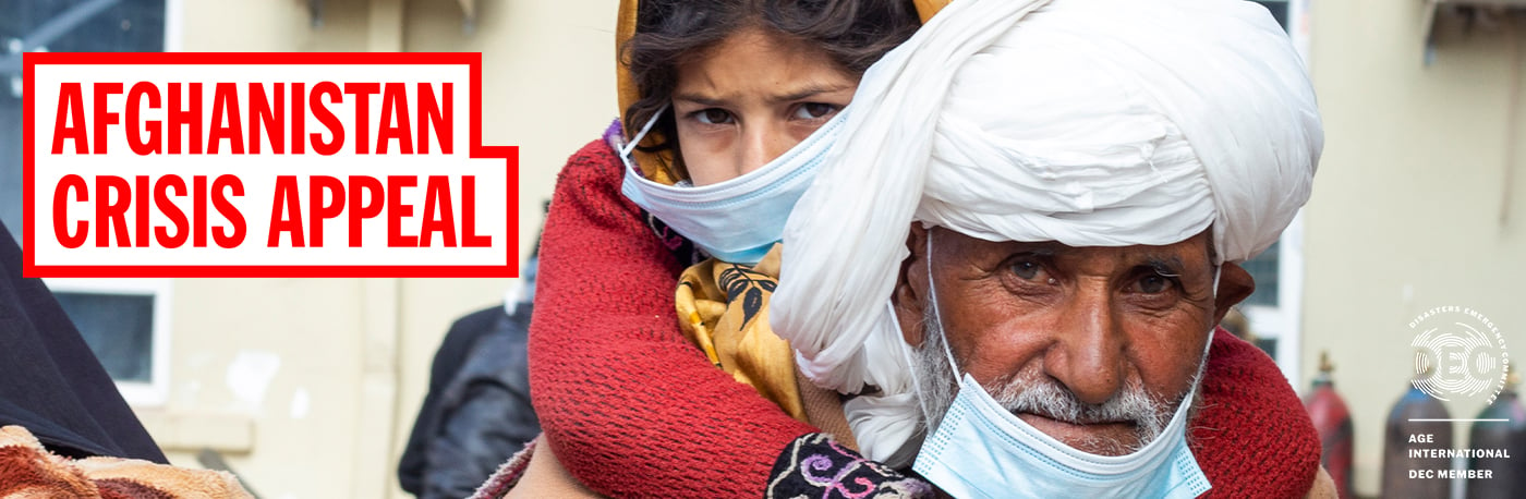 An older man carrying a young girl on his back in Afghanistan.