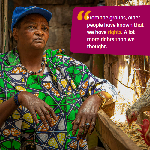 Photo of an older woman in a green dress stood next to a chicken coop. Text: "From the groups, older people have known that we have rights. A lot more rights than we thought"