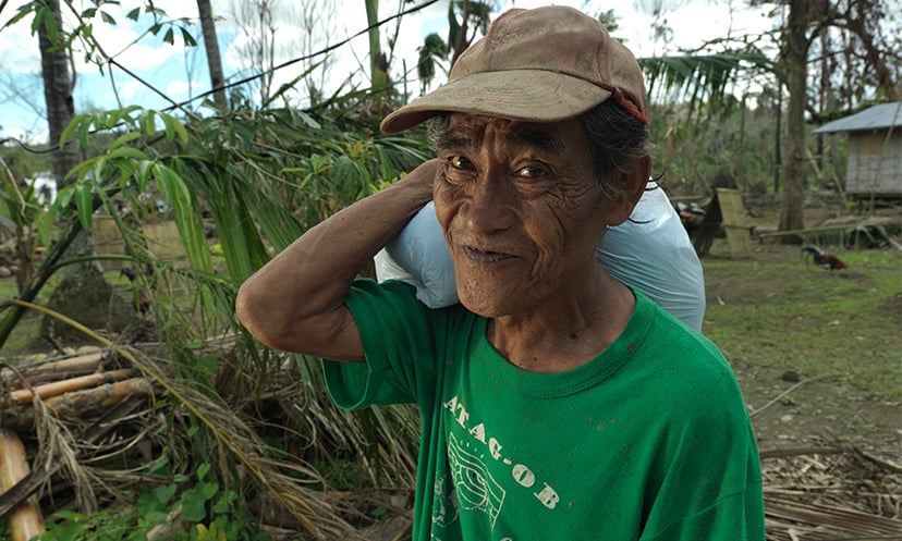 Older person carrying a food pack in the Philippines